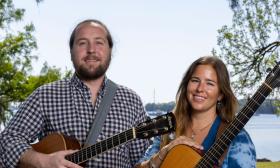 Jim Johnston and Aslyn Barringer with their guitars, with Florida river view in background