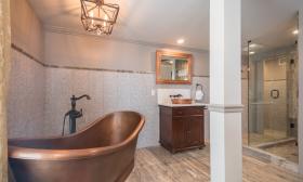 This luxury bath at the Bayfront Wescott House features a large shower and a copper-colored slipper tub
