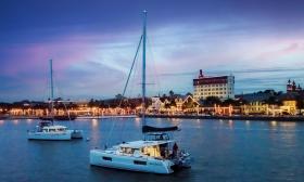 A luxury catamaran from St. Augustine Sailing, cruising past the bayfront with passengers on a Nights of Lights Charter