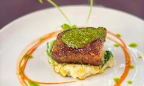 An artfully plated seafood sample with pesto and a corn pudding 
