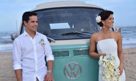 Bride and groom posing in front of a Volkswagen bus on the beach