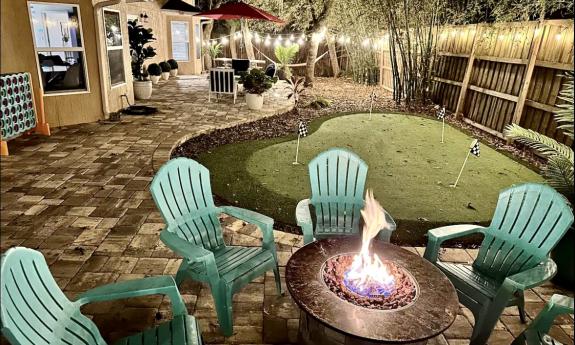 The firepit at Casa Del Sol has comfortable green chairs on a paved patio