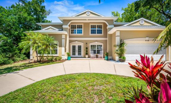 This two-story tan and cream building with circular driveway is Casa Del Sol, a vacation rental available through Vilano Luxury Properties