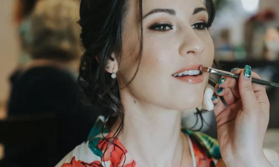 makeup artists applying finishing touches to a woman's lips