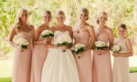 Bridal party posing outside with white floral arrangements