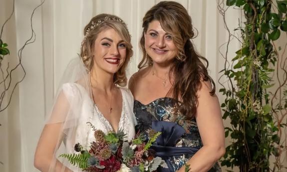 Bride with her mother in front of wedding backdrop