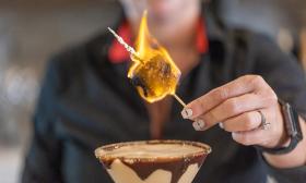 A bartender serving a S'mores Martini with a flaming marshmellow