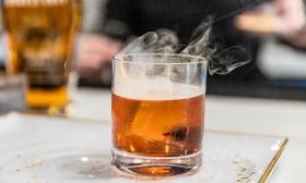 A smoked and smoking Old Fashioned with Four Roses Bourbon, simple syrup, and Angostura Bitters