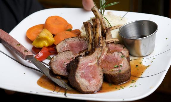 A rack of lamb and a side of vegetables served at Raintree Restaurant