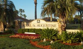 The entrance to Royal St. Augustine Golf Club with a large sign, palm trees, and greenery