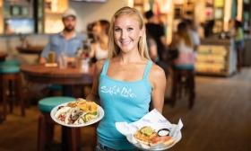 A server at Salt Life Food Shack with two meals for guests