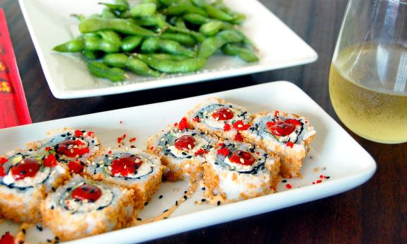 Salt Life's crab avocado roll with edamame and a glass of wine in the background