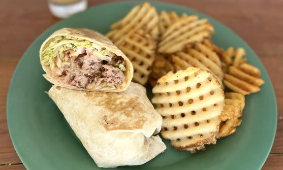 A cheeseburger wrap with waffle fries on the side