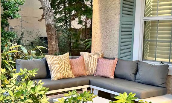 The front porch of the Paraiso features a secluded corner, with a grey settee among the greenery