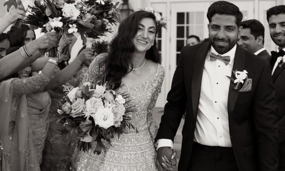 Couple smile for a photo while walking through a celebrating crowd