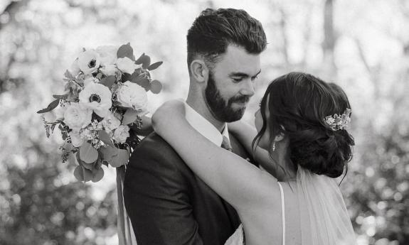 Bride looking at groom with her arms wrapped around his shoulders