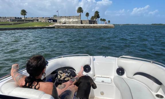 A woman and her dog relax on a private boat charter