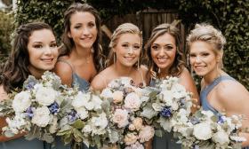 Bridal party posing with floral arrangements