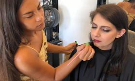 Beauty artist applying makeup to a bride's lips