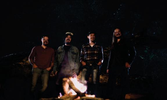 Tophouse stands near a burning fire-it and smiles for the camera. 