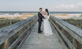Bride and groom posing on beach access bridge