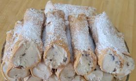 Cannolis sprinkled with powdered sugar arranged in a bowl