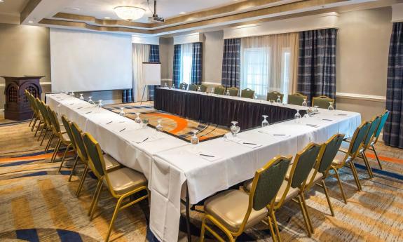 A board meeting room set up with tables, chairs, and a projector