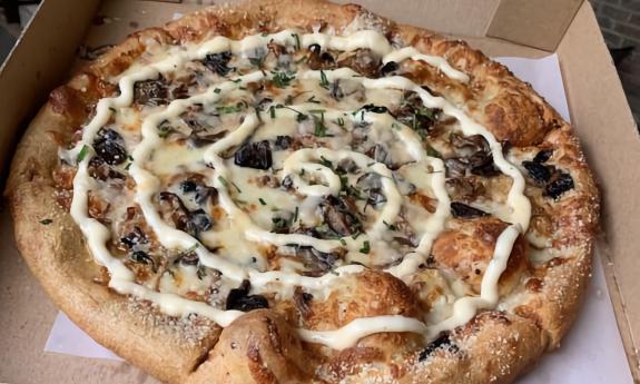 A Holy Shiitake pizza in a to-go box