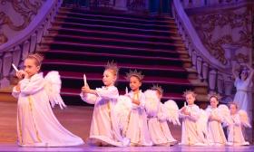 Young ballet dancers, the angels in Nutcracker, holding candles in front of a grand staircase