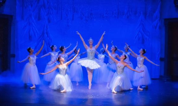 Dancers against a blue backdrop on stange in the snow scene in Nutcracker