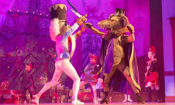 The Nutcracker and the Mouse King fight with swords on stage in the Nutcracker