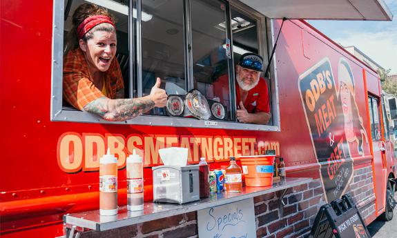 Jessie Kresa, on the left, gives a thumbs up while serving up meals out of the food truck