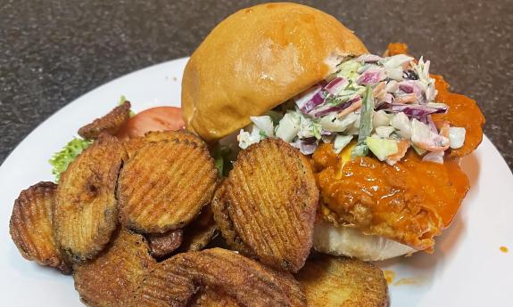 A buffalo chicken sandwich with a side of crispy onions