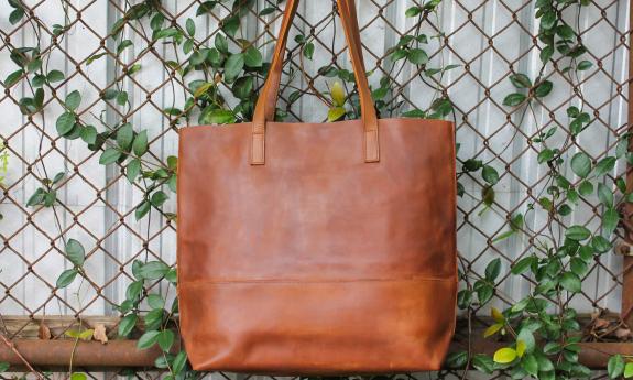 A brown leather bag from rethreaded hanging from a trellis with greenery