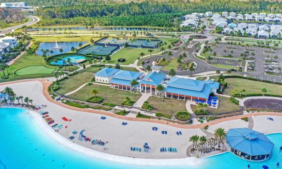 Aerial view of the members-only waterfront club house and the surrounding putting green, tennis courts, and community parking lots