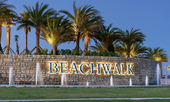 Community sign with a water display and palm tree landscaping