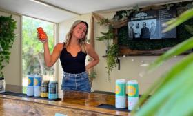 Friendly bartender serving craft beer at a mobile bar with green plants and television in the background