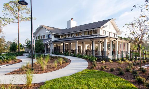 TrailMark's modern clubhouse with a grey roof, surrounded by manicured greenery and a winding path