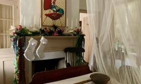 A bedroom with stockings and garland bordering the fireplace