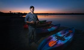 Ben Brandao, owner of GeoTrippin' standing next to kayaks at sunset