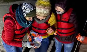 Kayakers dressed for cold weather, learning about bioluminescent sea creatures