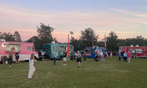 Four food trucks in different colors arranged on Station Field in Nocatee for Food Truck Friday