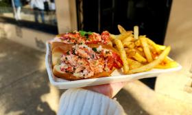 A lobster roll and a side of fries presented on a tray