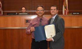 Chris Bodor accepts a proclimation recognizing National Poetry Month from a County Commissioner Roy Alaimo.