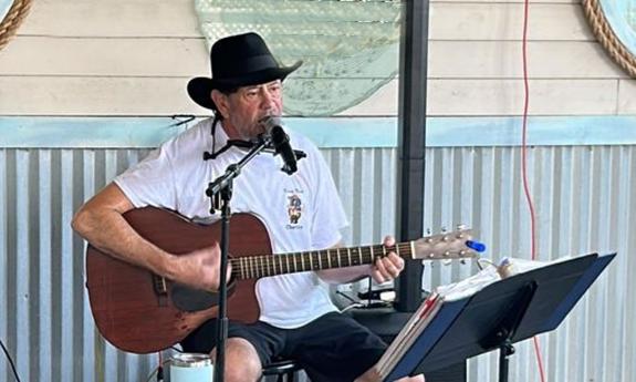 Musician Allen Arena playing guitar at a fish camp