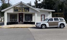 The Corner Market store building with a car parked out front