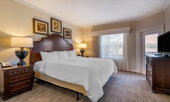 A brown and beige bedroom set lit up by the lamps on the end tables