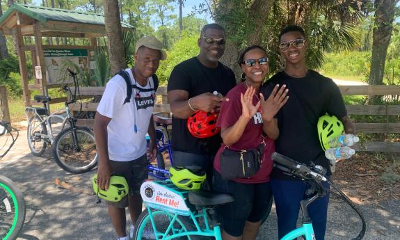 Four adults smiling near a bend in the trail while on an outing with Island Life Bikes