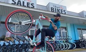 One of the team at Island Life Bikes, pops a wheelie in front of the store