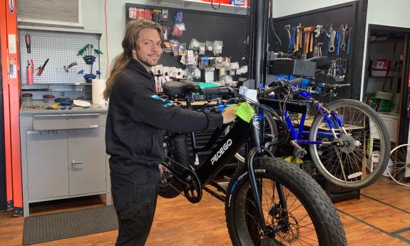 A bike technician repairs a black bike with fat tires